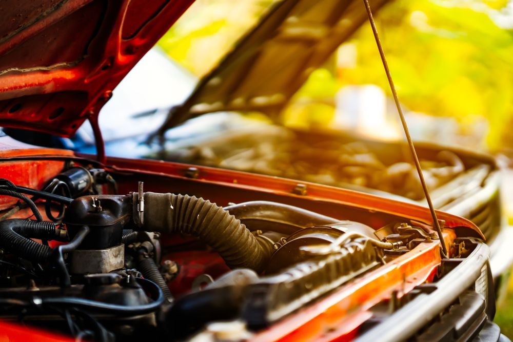 Red car engine bay with hood open, showing engine and surrounding components — P.K. Head Servicing & Reconditioning in Shellharbour, NSW