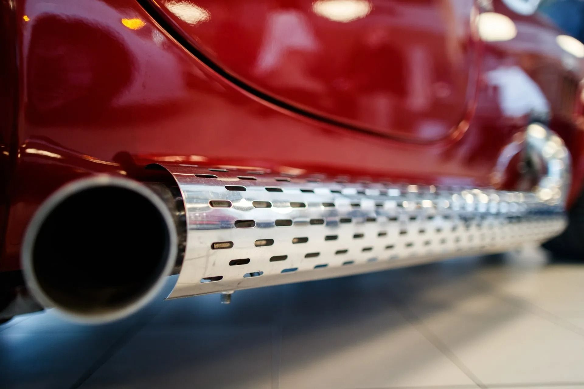 Shiny Chrome Side Exhaust Pipe on a Red Car — P.K. Head Servicing & Reconditioning in Shellharbour, NSW