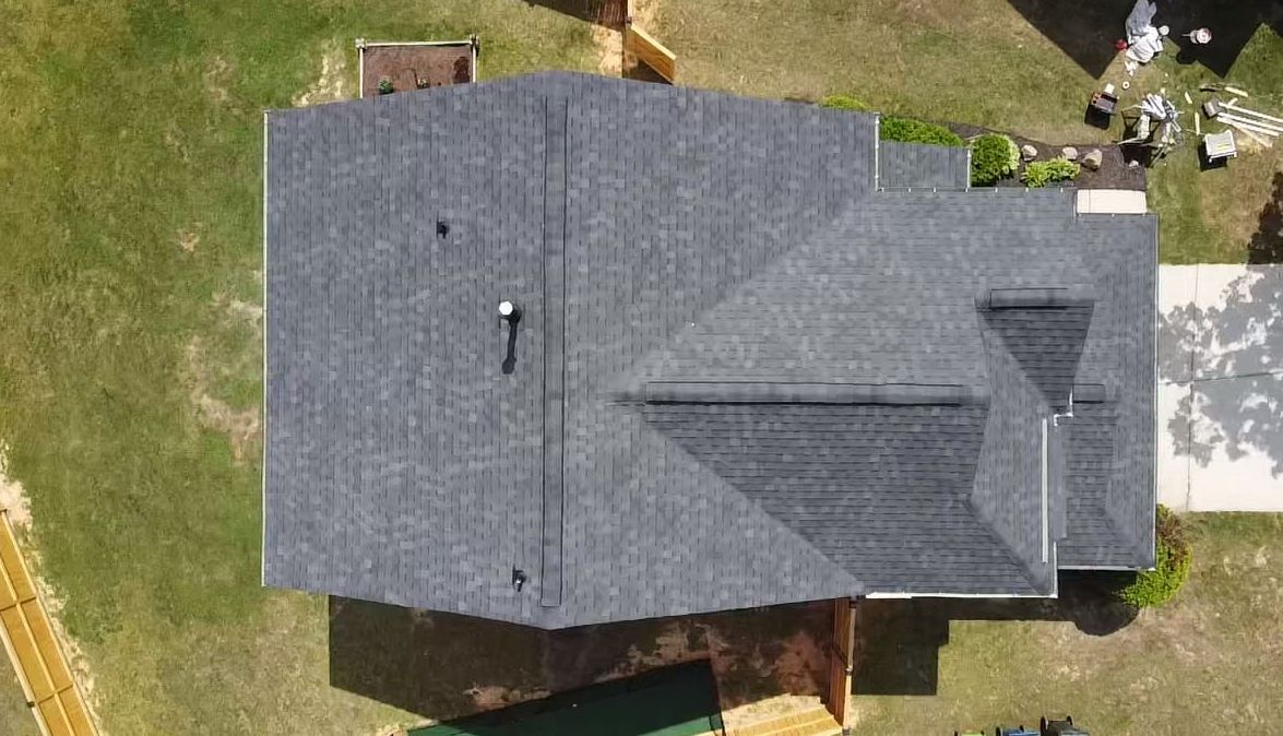 Overhead view of a house with a gray shingled roof, set on green grass.