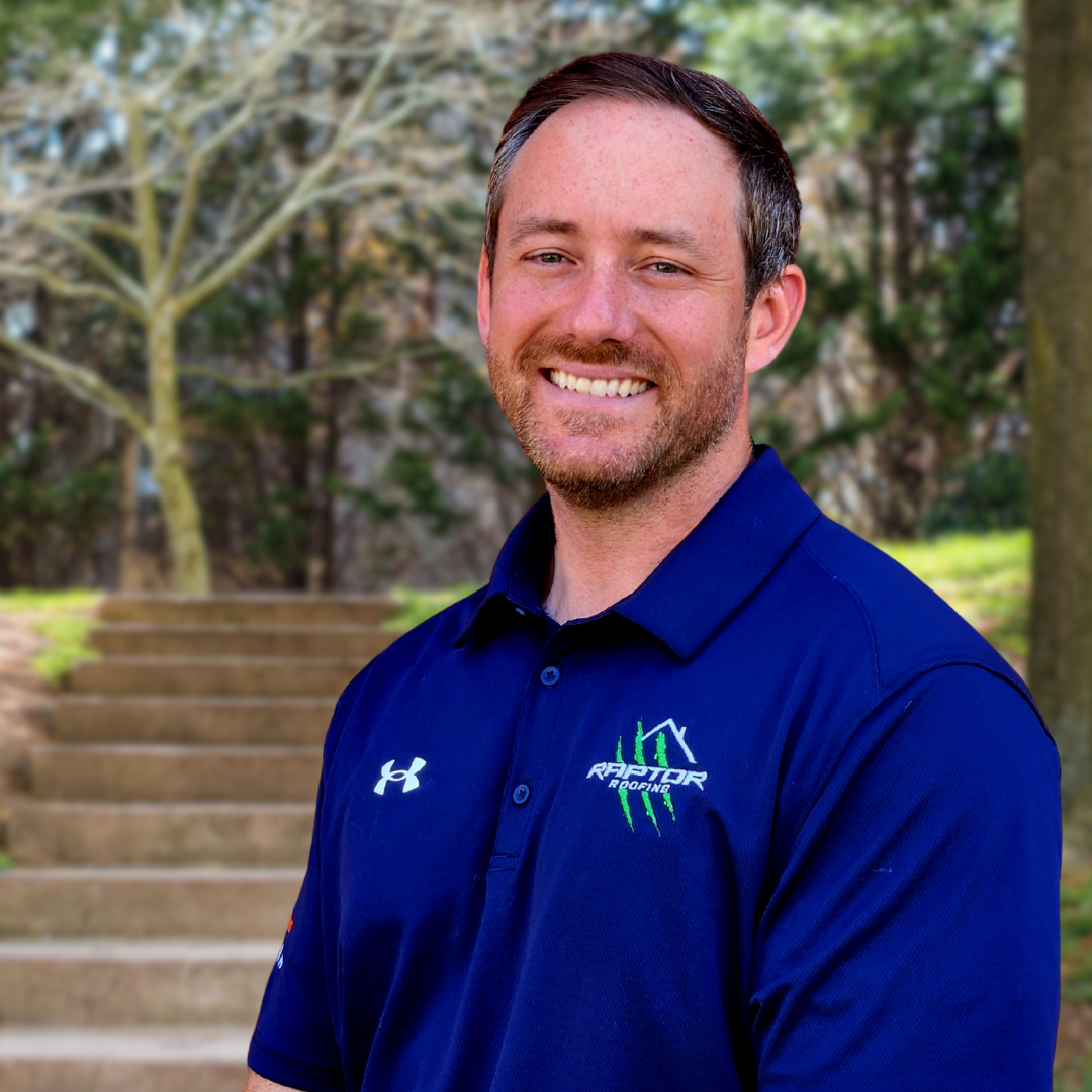 Man in blue polo shirt smiles outdoors near stairs.
