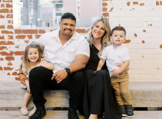 A family is posing for a picture while sitting on a bench.