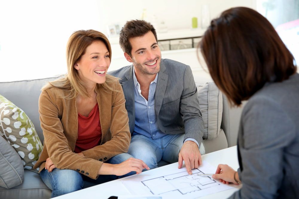 Couple Smiles While Reviewing Blueprints With a Professional — Curtis Strata in Yamba, NSW