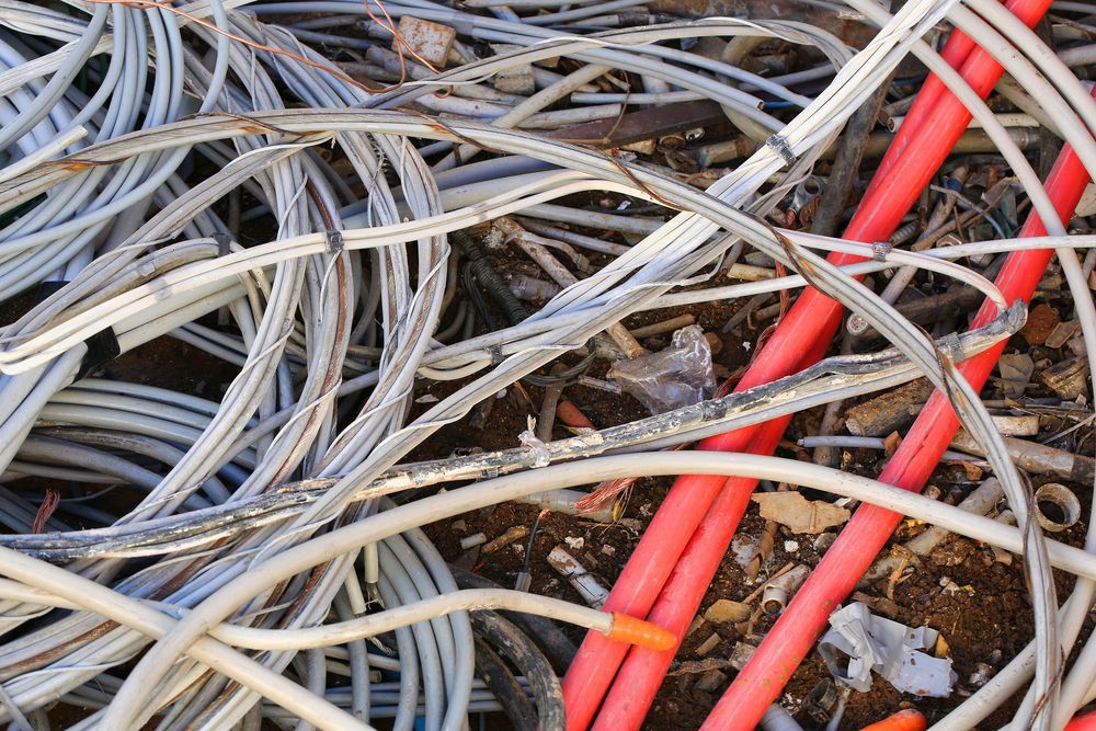 Pile of Gray and Red Electrical Wires on Brown Ground — Independent Scrap Metal Pty Ltd in Murwillumbah, NSW