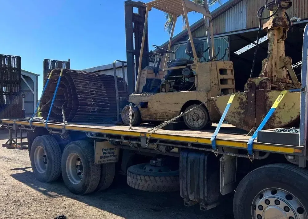 Flatbed Truck Carrying a Forklift and Large Circular Metal Objects — Independent Scrap Metal Pty Ltd in Byron Bay, NSW