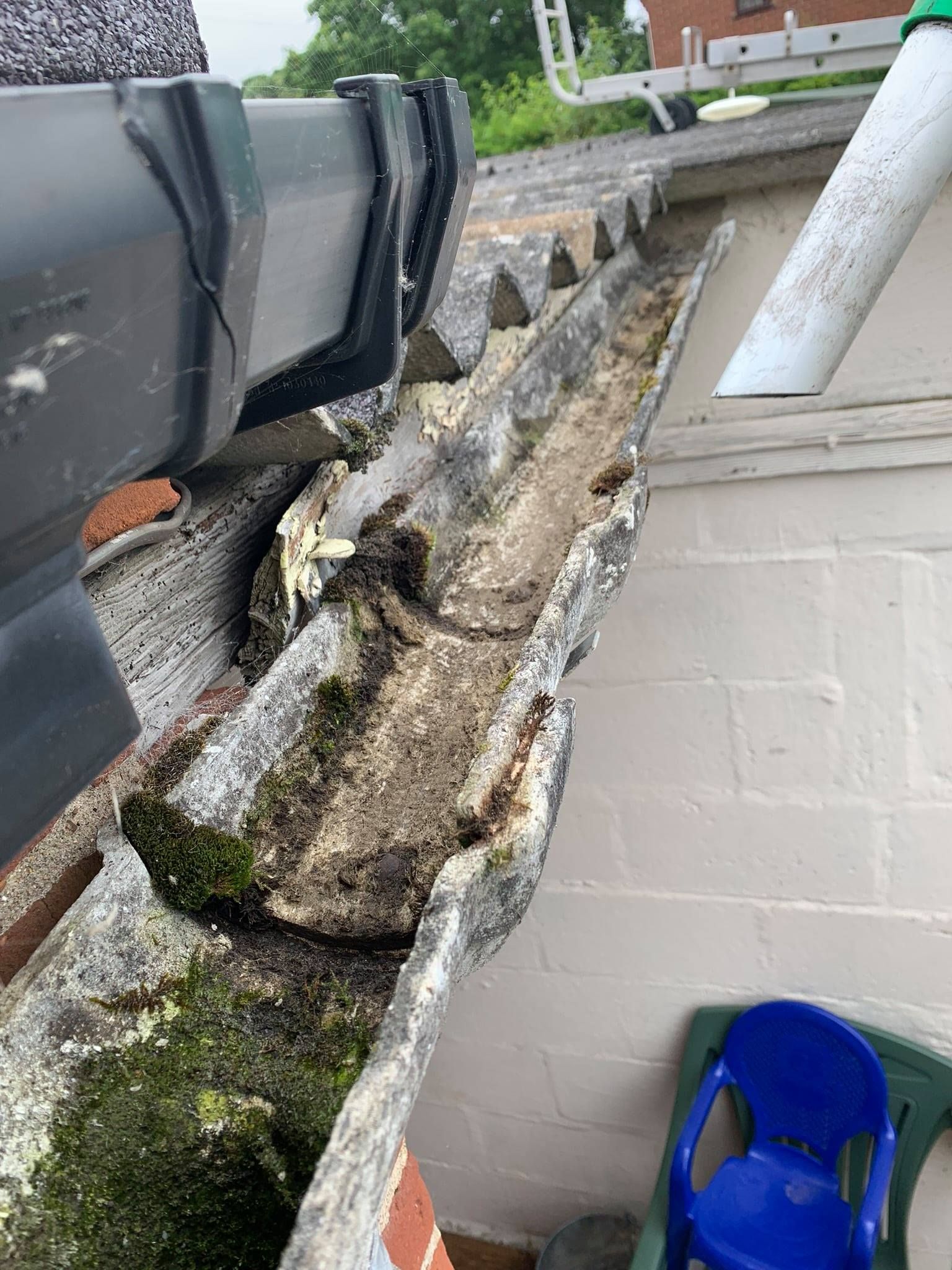 Close-up of the same gutter, now cleared of most moss and debris, next to the drainpipe on the roof.