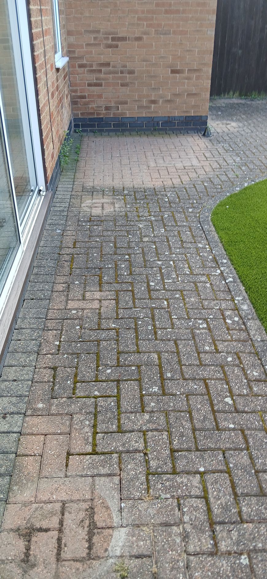 A block paved patio in front of a brick house before being pressure washed by benchmark property services.