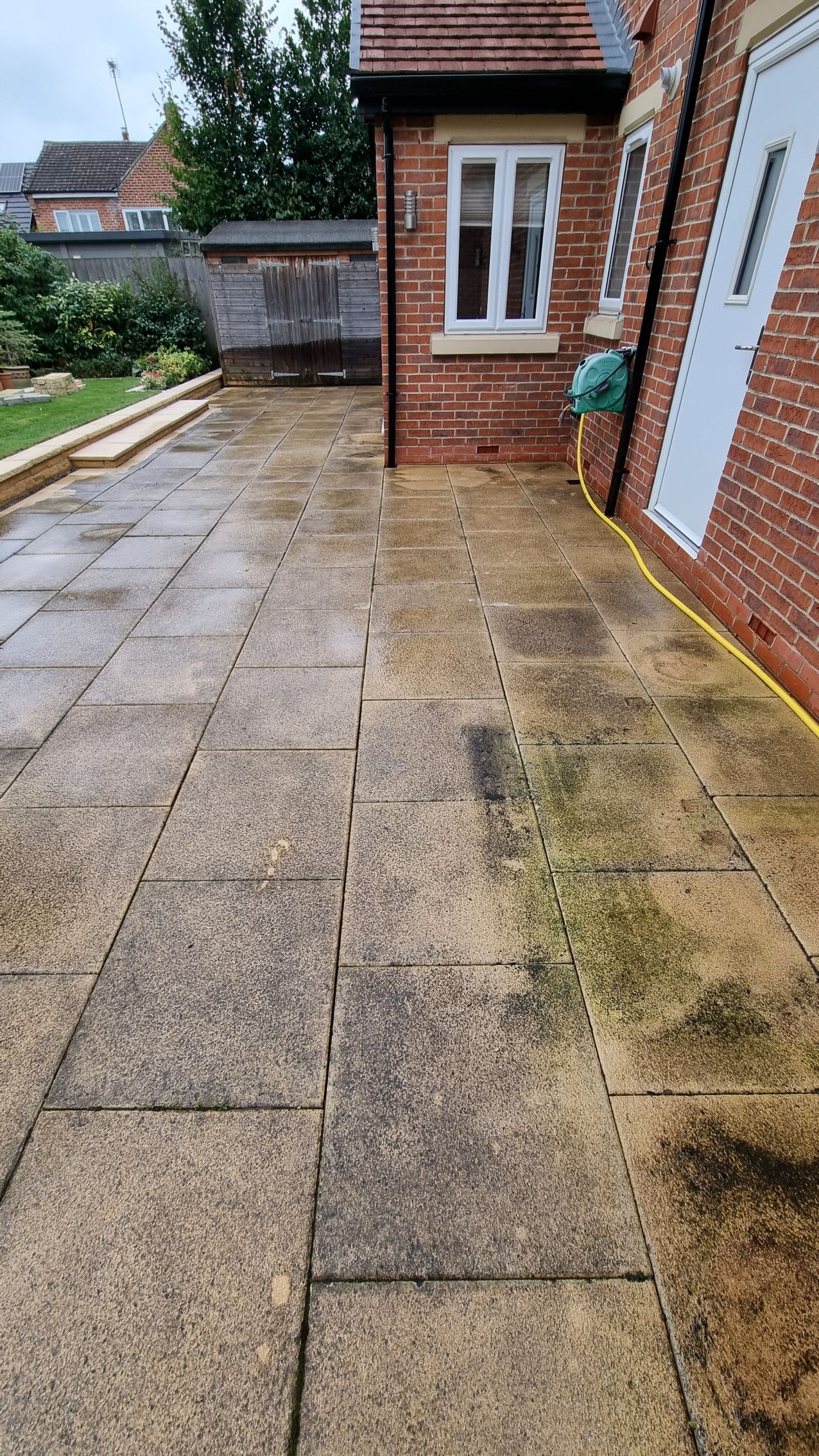 A block paved driveway in front of a brick house before being pressure washed by benchmark property services.