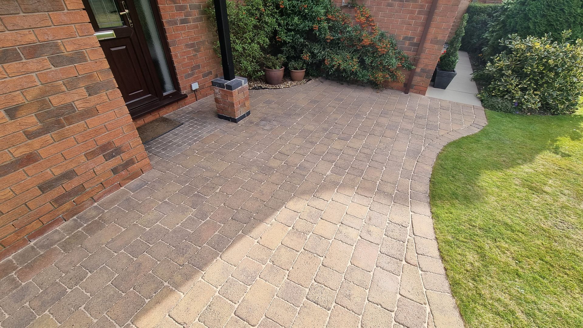 A block paved driveway after being cleaned, leading to the front door of a house.