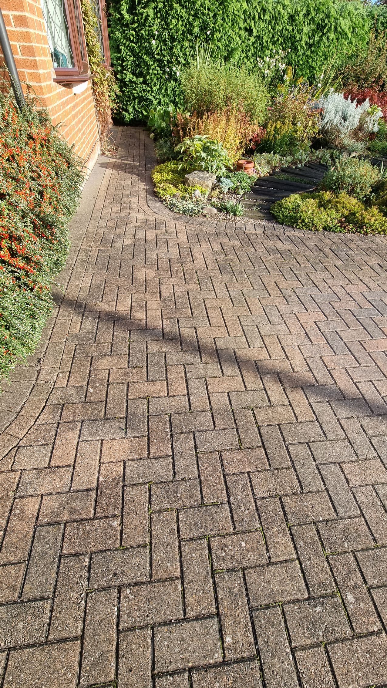 A block paved driveway in front of a brick house before being pressure washed by benchmark property services.