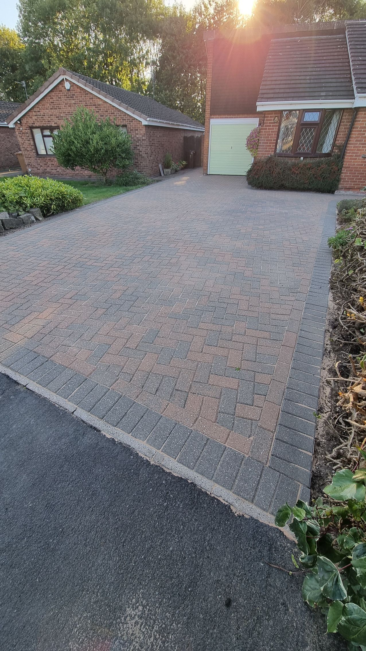 A block paved driveway in front of a brick house before being pressure washed by benchmark property services.
