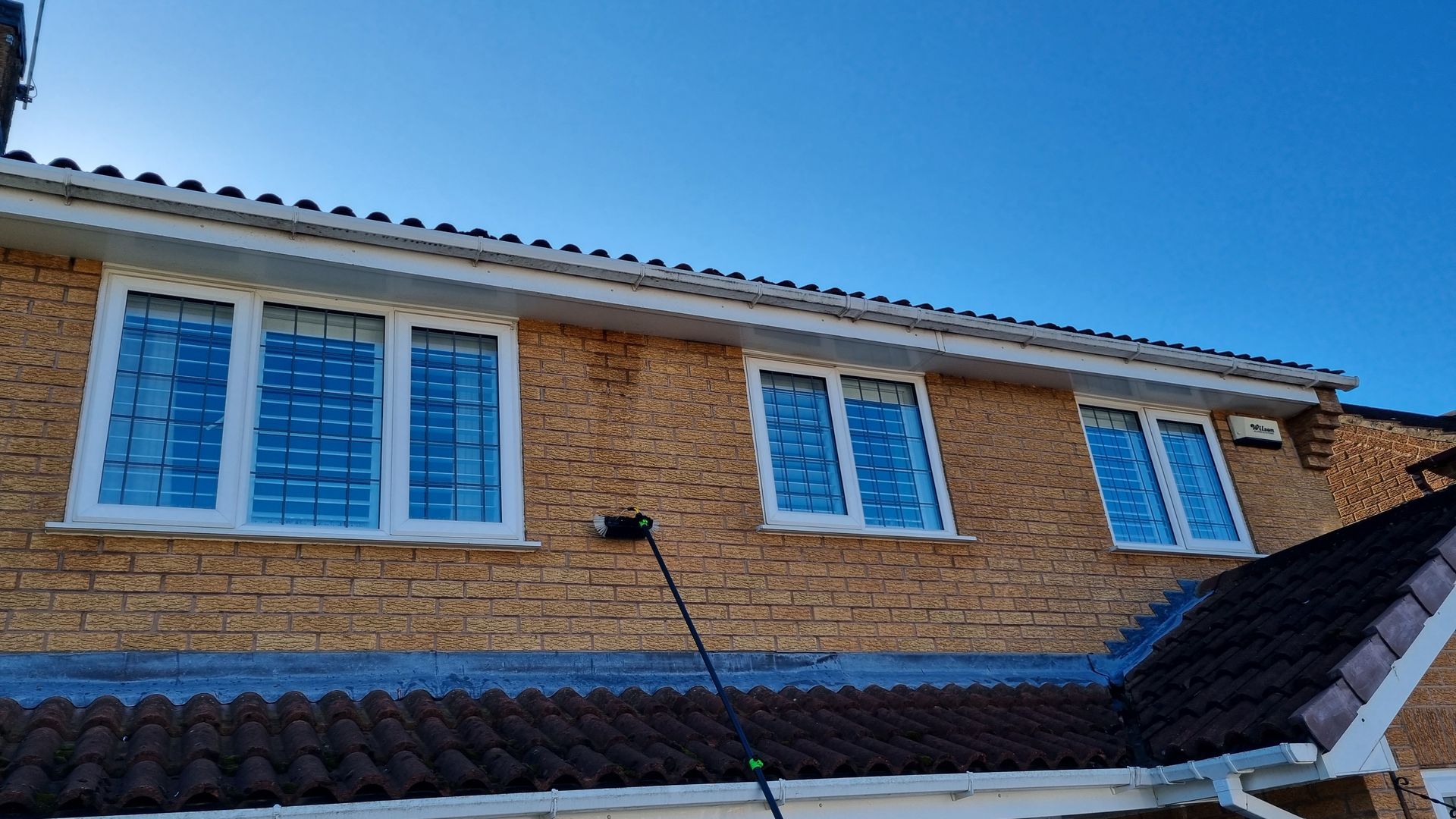 A brick house with three windows and a roof.