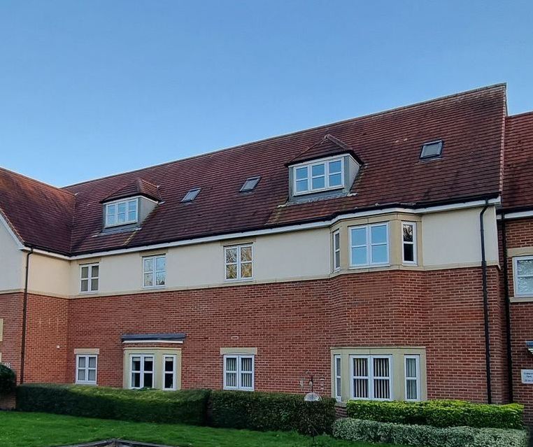 A large brick building with a tiled roof and many windows that need cleaning.