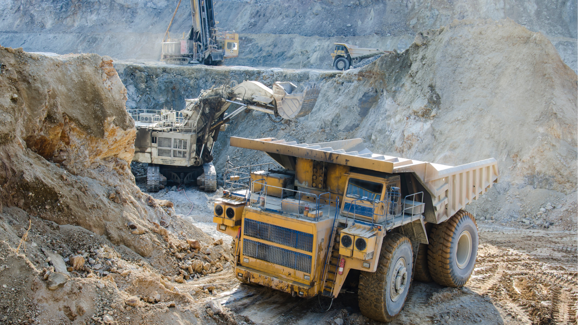 Mining trucks hauling dirt in a dusty open-pit quarry