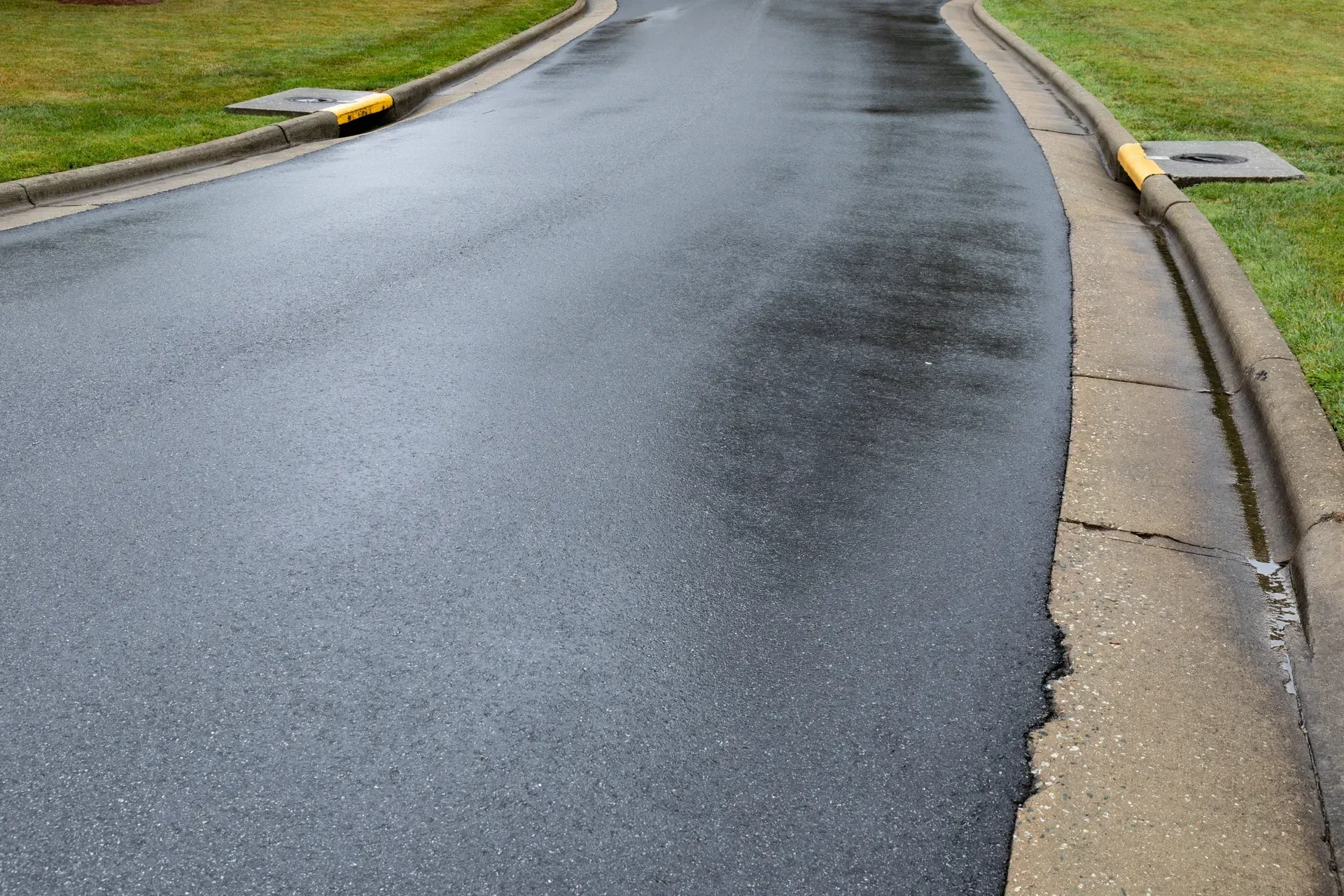 Damaged asphalt road with a cracked edge and curb on the right side