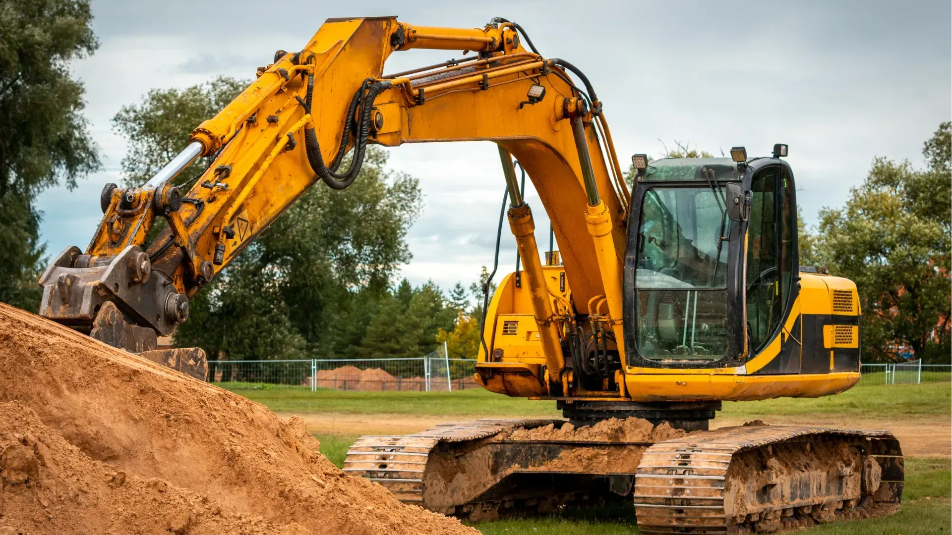 Yellow excavator working on a dirt pile at a construction site