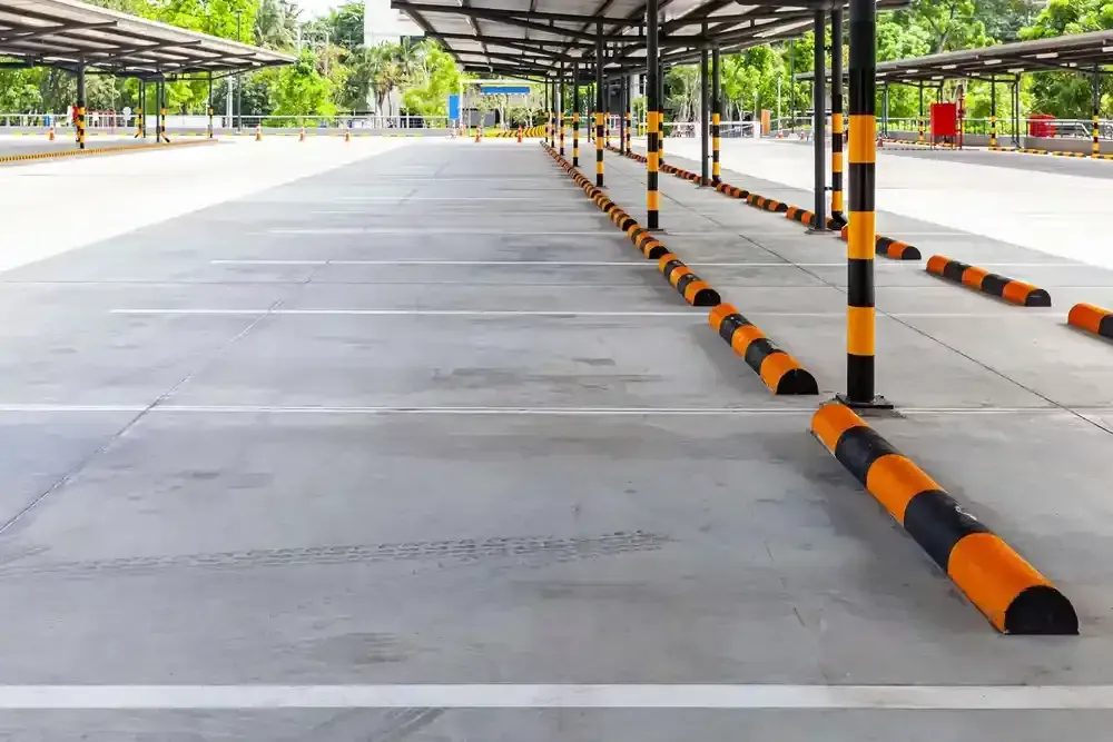 Empty covered parking area with concrete lanes and black-yellow striped barriers