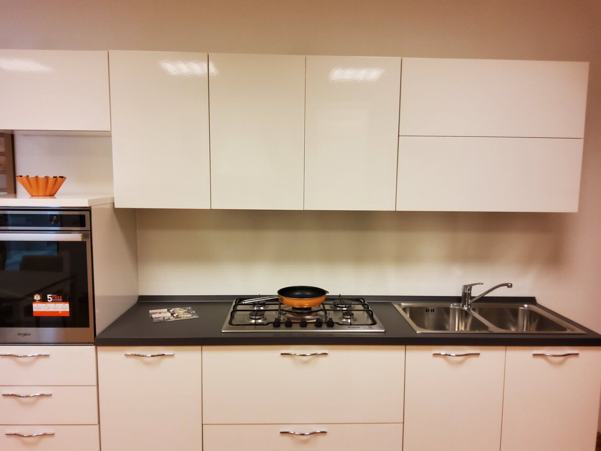 Mobili da cucina e ripiani bianchi con forno, piano cottura e lavello integrati.