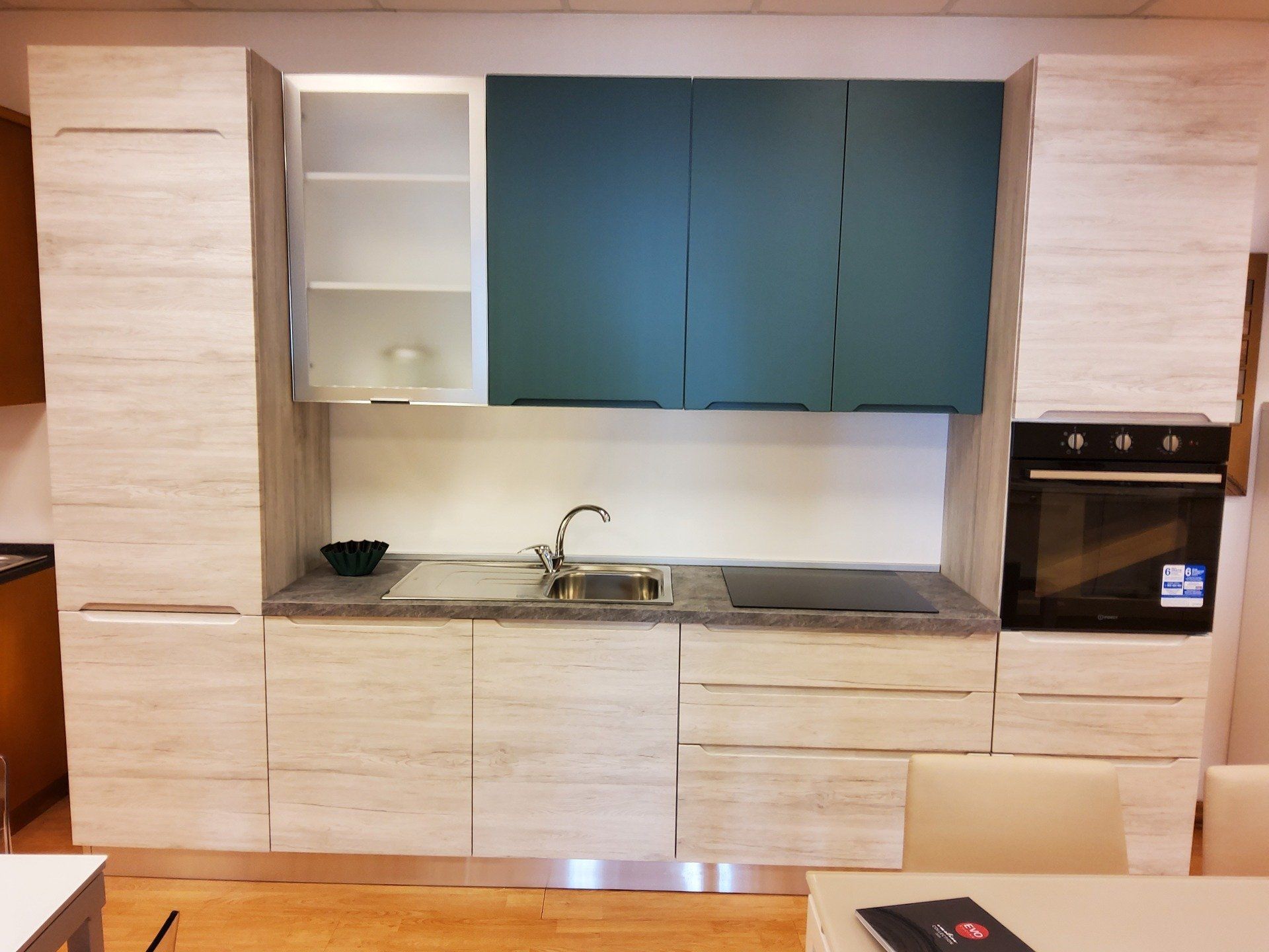 Mobili da cucina moderni con finiture bianche, verde acqua e grigie. Include forno, lavello e piano cottura.