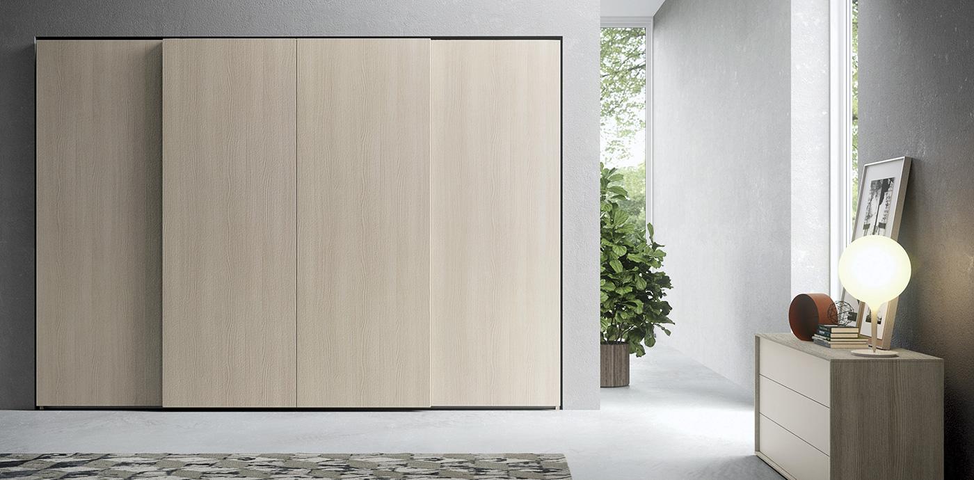 Camera da letto con un grande armadio scorrevole in legno, un comodino con lampada e una finestra aperta con verde.