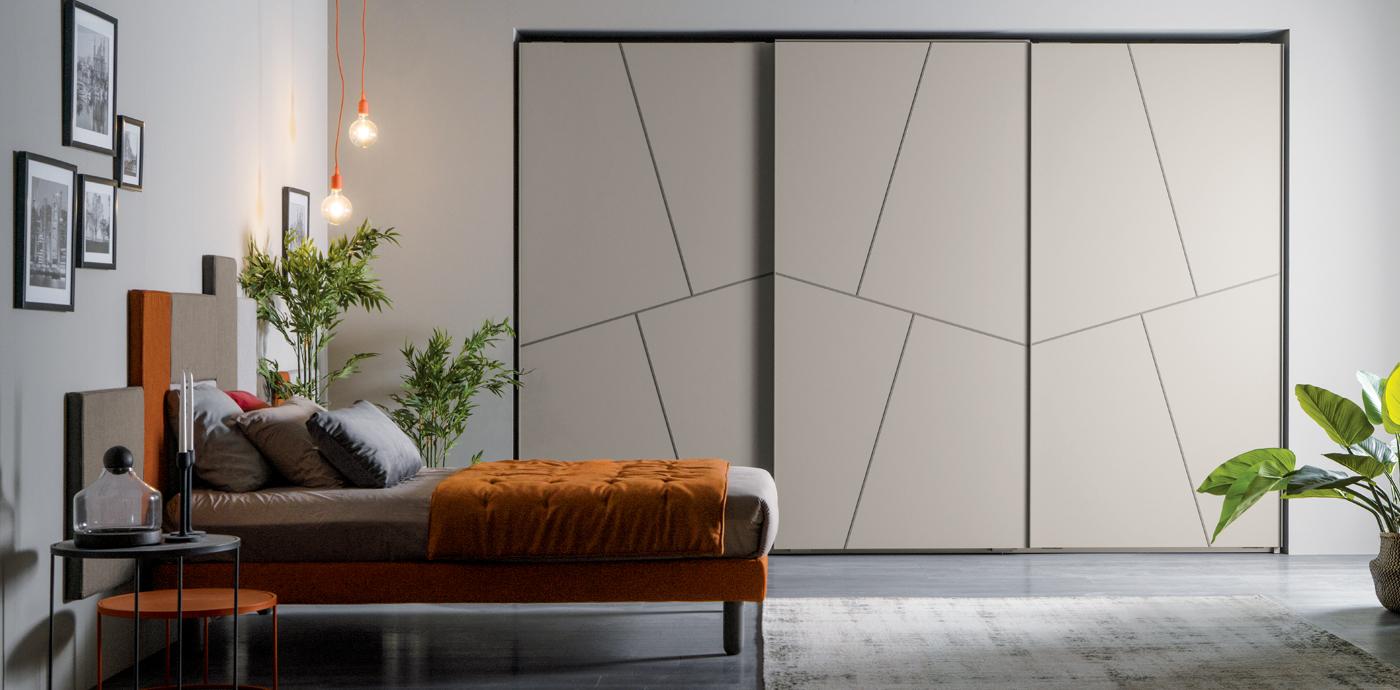 Camera da letto con letto, moderno armadio con ante scorrevoli, piante e opere d'arte. L'arredamento è caratterizzato da toni caldi.