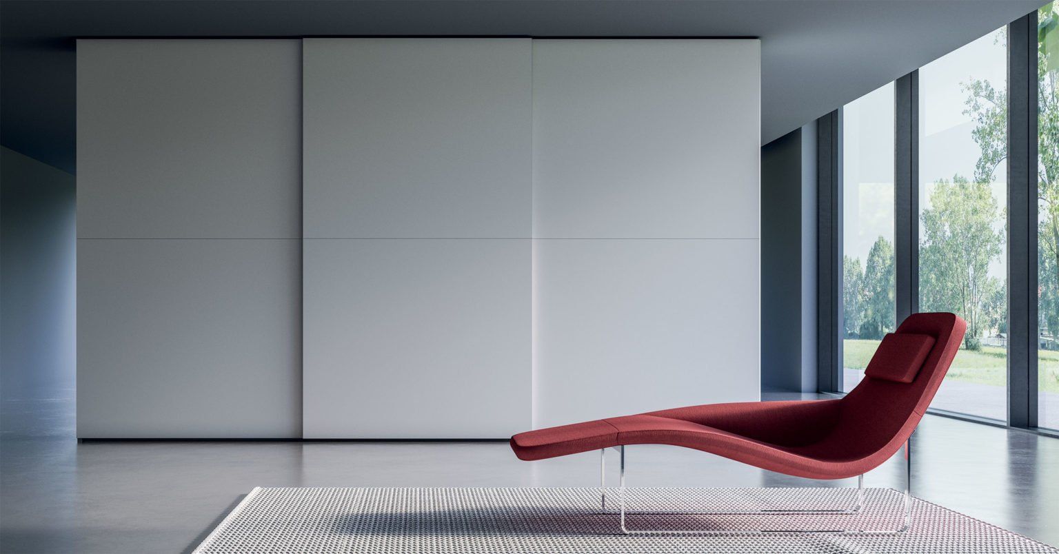 Camera moderna con armadio bianco, chaise longue rossa sul tappeto e ampie finestre.