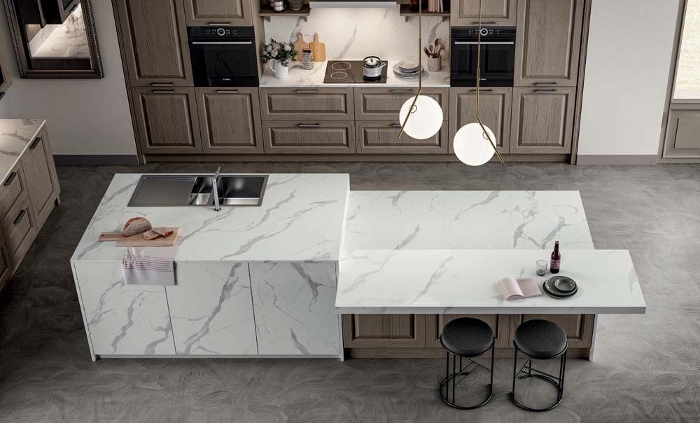 Vista dall'alto di una cucina moderna con ripiani in marmo, mobili in legno e due isole.