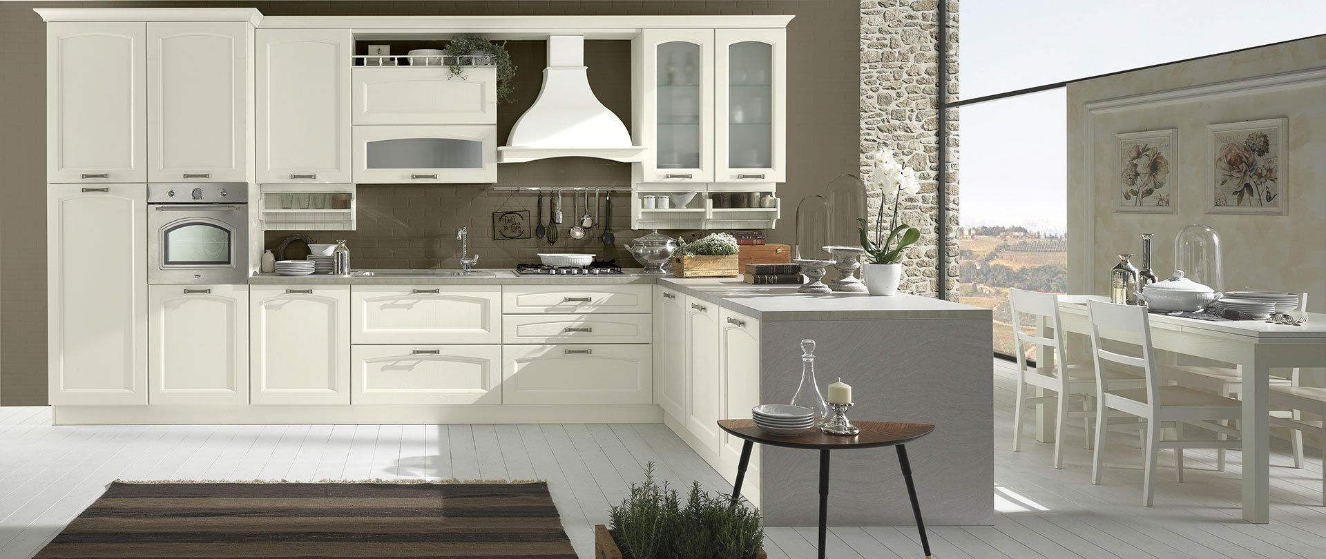 Cucina color crema con isola e zona pranzo accanto a una grande finestra.