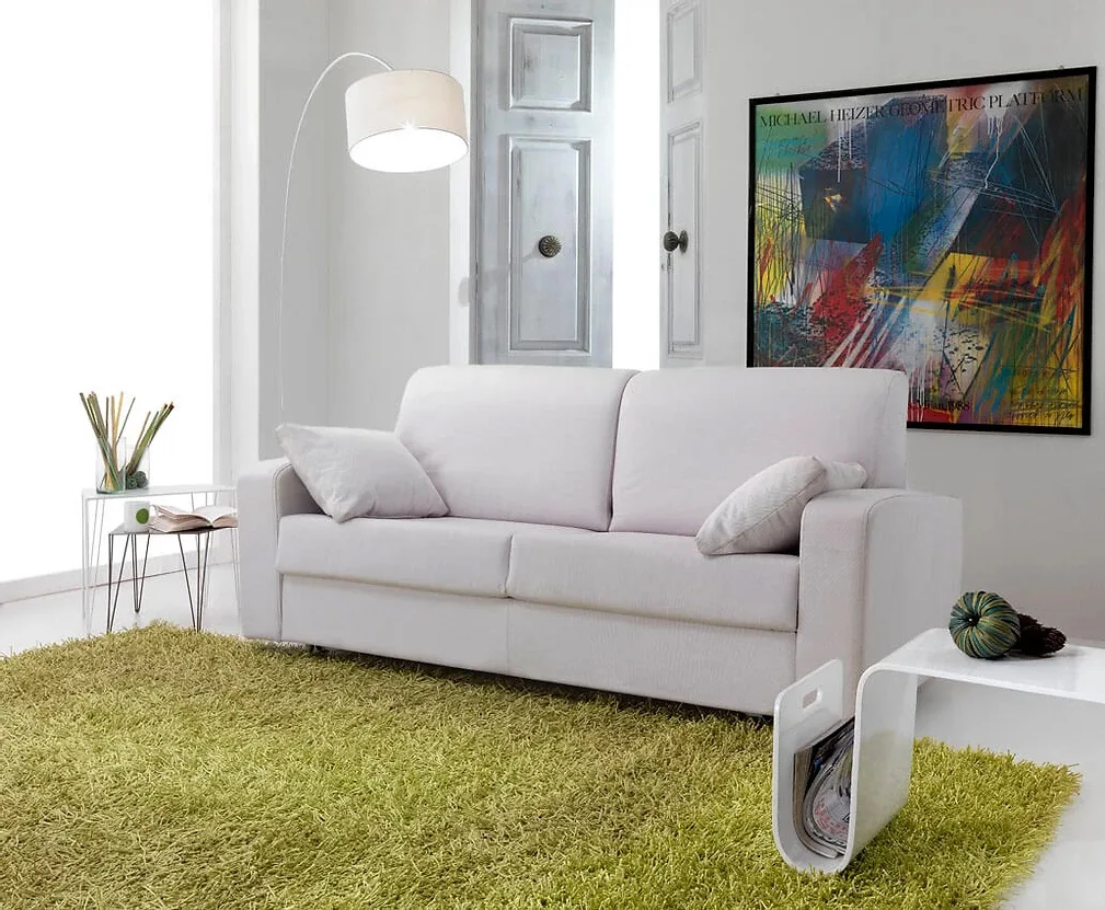 Soggiorno con divano bianco, tappeto verde, opere d'arte astratte e lampada da terra.
