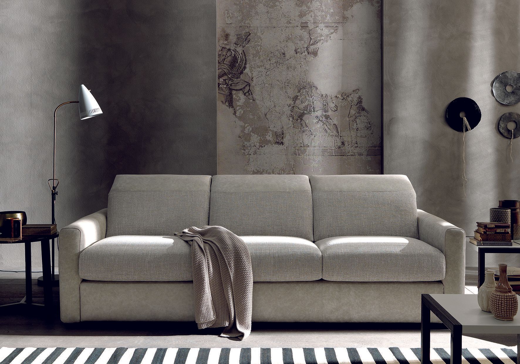 Divano grigio con coperta, in un soggiorno moderno.