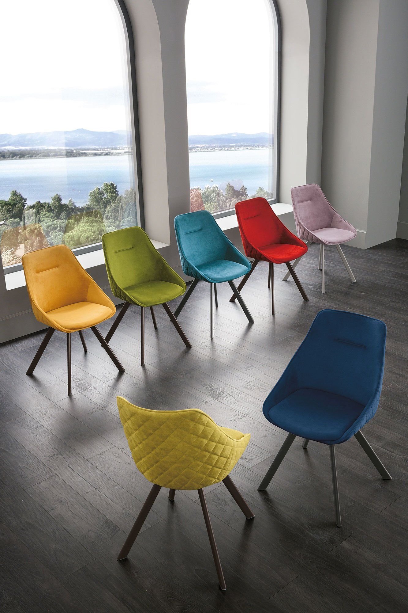 Assortimento di sedie colorate in una stanza con una finestra con vista panoramica.