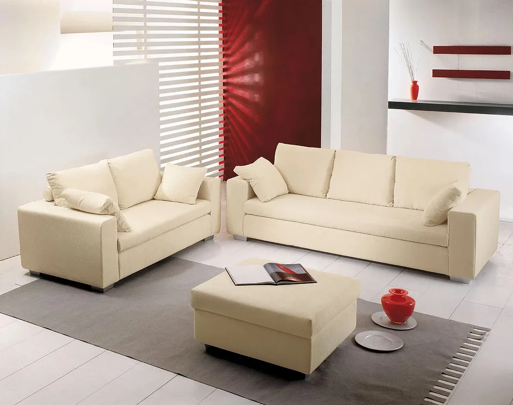 Set da soggiorno moderno color crema: divano, divanetto, pouf, con tappeto grigio e parete decorativa rossa.