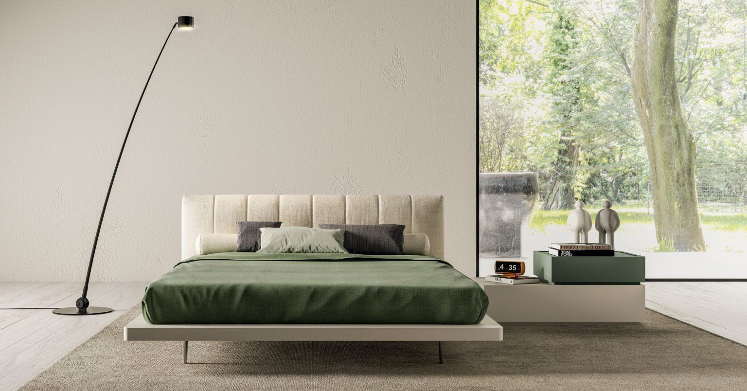 Moderna camera da letto con letto, lampada da terra e comodino di fronte a un'ampia finestra con vista sul giardino.