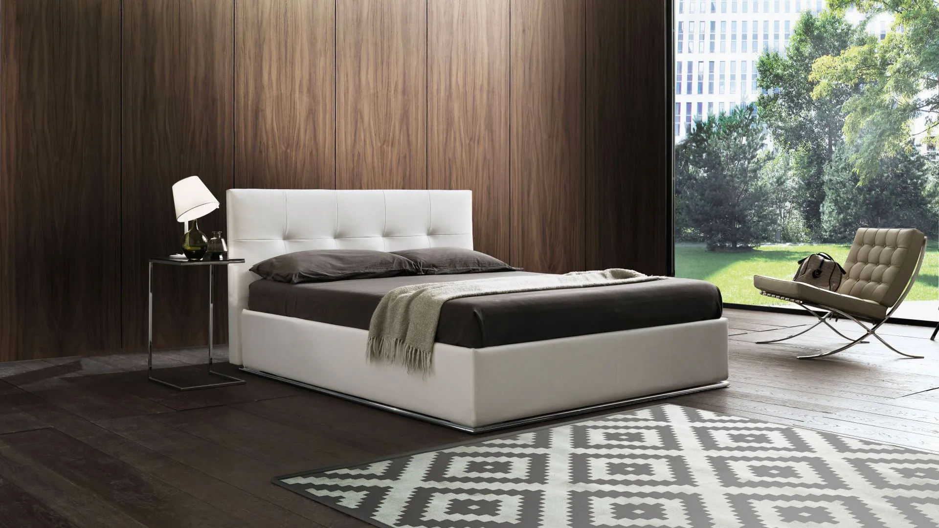 Letto imbottito bianco con testiera trapuntata in una camera da letto moderna con tappeto decorativo e sedia.
