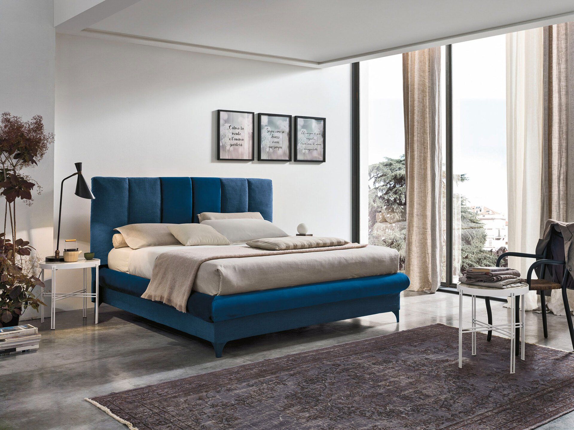 Letto imbottito blu in una camera da letto minimalista con una grande finestra.