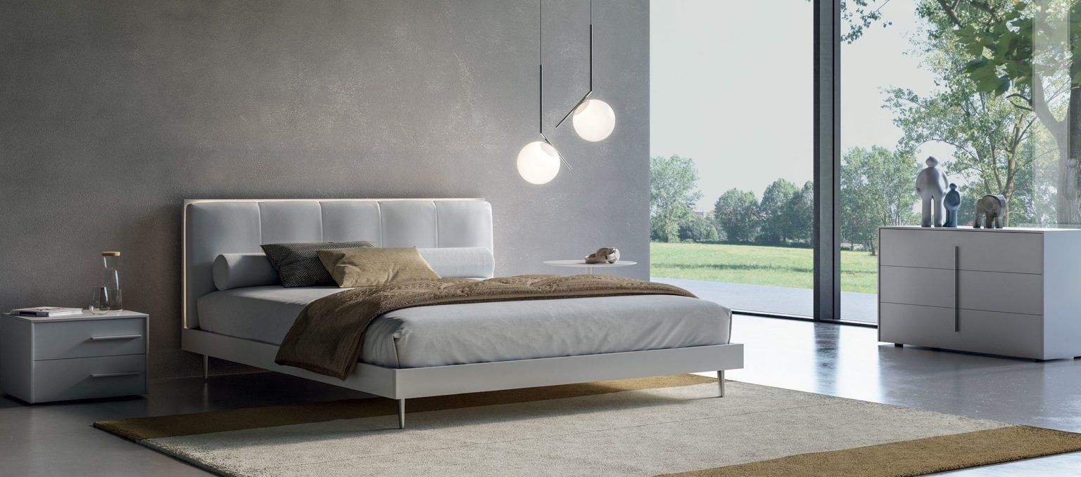 Camera da letto con mobili bianchi, ampia finestra e arredamento minimalista.