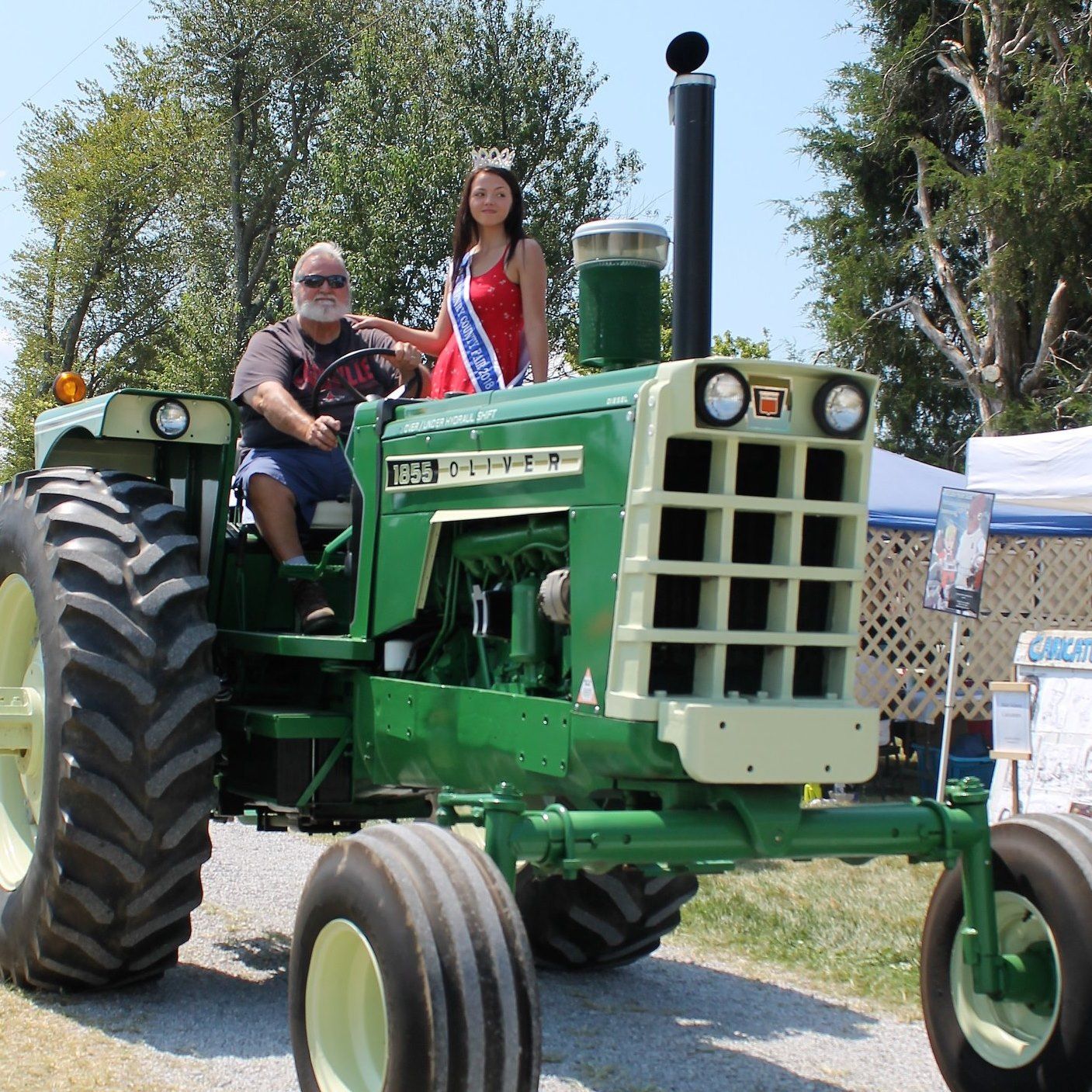 A woman in a red dress is sitting on top of a green tractor