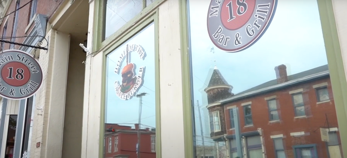 A store front with a reflection of a brick building in the window.