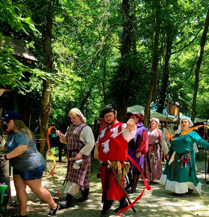 A group of people dressed in costumes are walking through a forest.