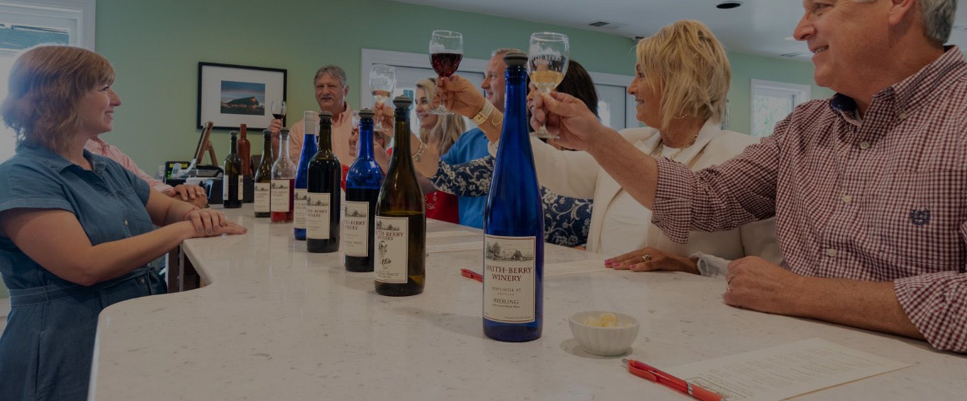 A group of people are sitting at a table with bottles of wine.
