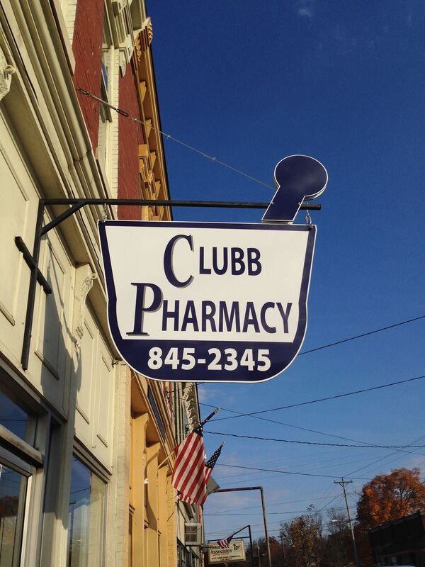 A clubb pharmacy sign hangs from the side of a building
