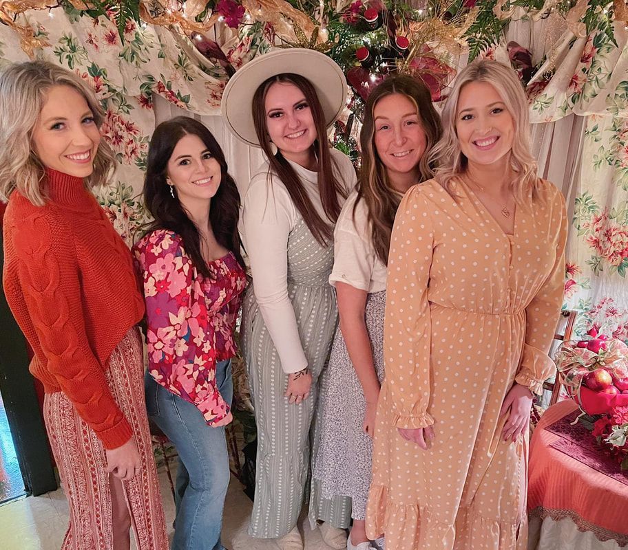 A group of women are posing for a picture in front of a christmas tree.