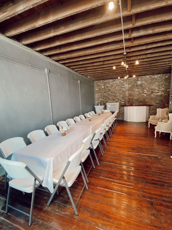 A long table and chairs in a room with a wooden floor.