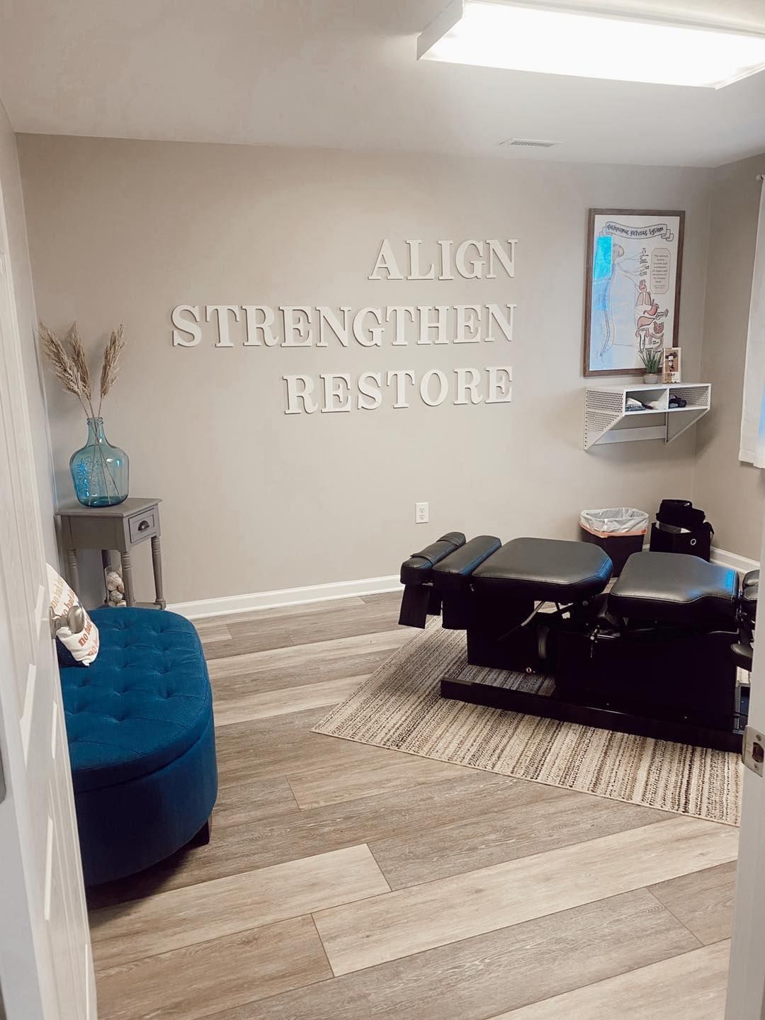 A room with a massage table and a sign on the wall that says `` align strengthen restore ''.