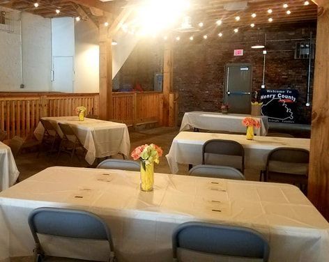 A room with tables and chairs and flowers on them.