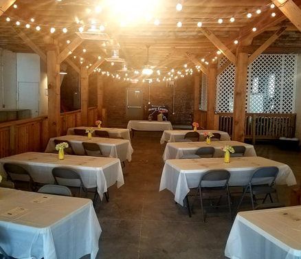 A large room with tables and chairs set up for a wedding reception.