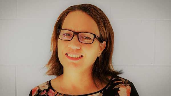 Angela Hodges, accountant, portrait - a woman wearing glasses and a floral shirt is smiling for the camera.
