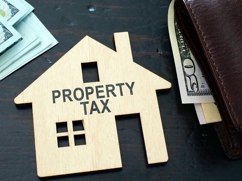 A wooden house with the words `` property tax '' written on it.
