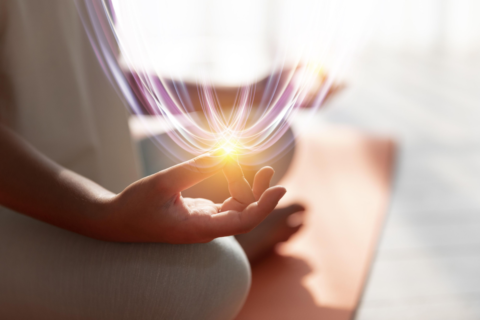 A person is sitting in a lotus position on a yoga mat with a light coming out of their hand.
