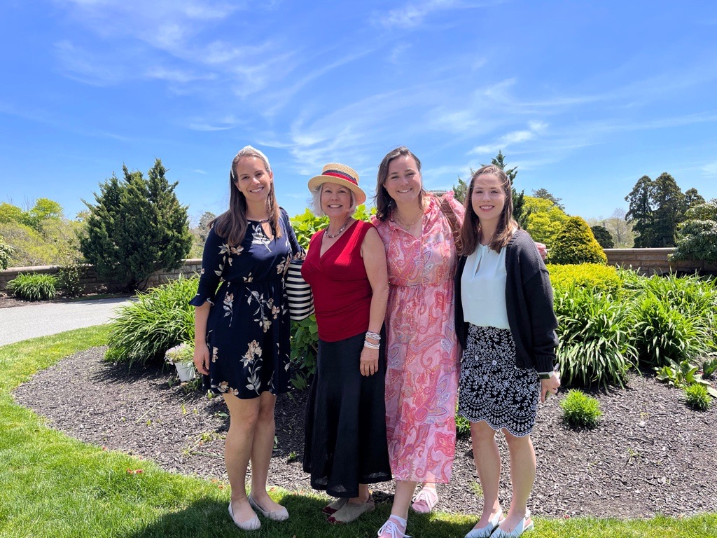 A group of women are posing for a picture in a garden.