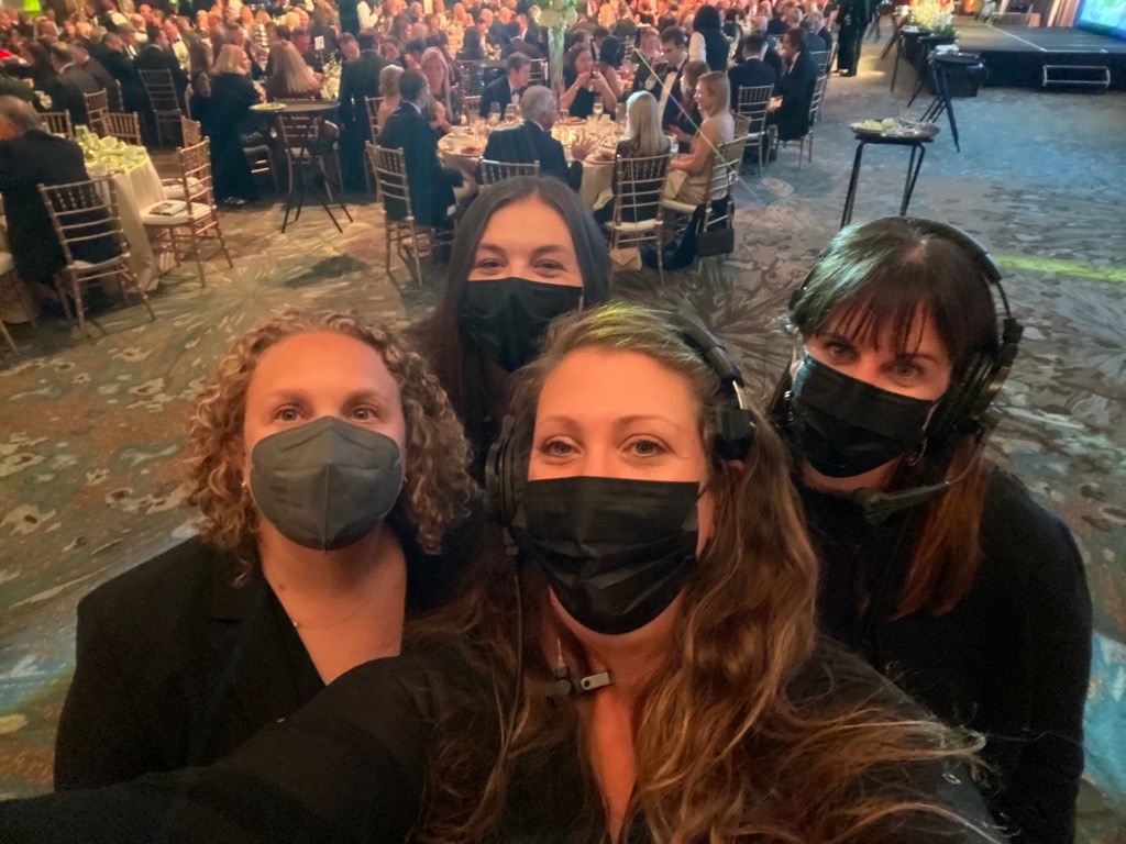 A group of women wearing face masks and headphones are posing for a picture.